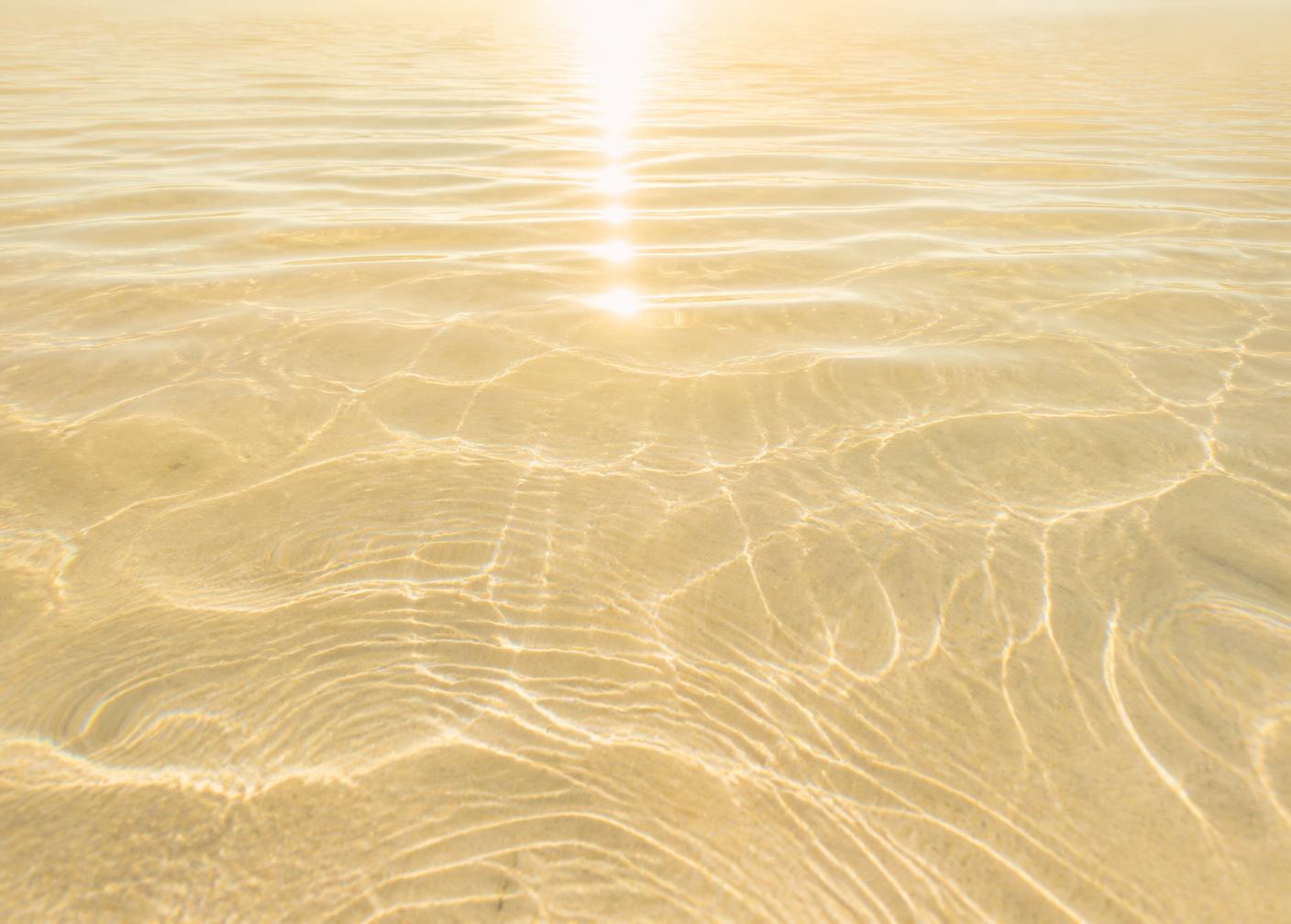 Crystal clear water with bright sunlight streaming across gentle ripples — luminous, calm, and open.